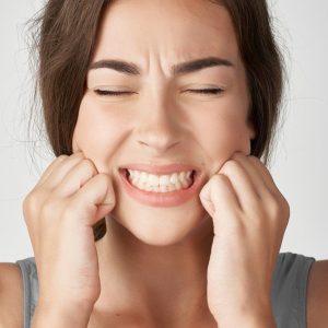 mujer presionando los dientes con dolor